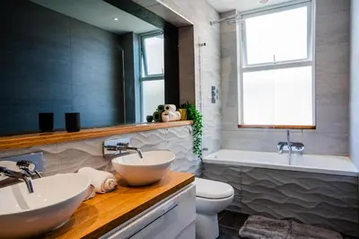 a bathroom with two sinks and a tub and a toilet at Central, stylish 3 bed apartment with sea views in Newquay