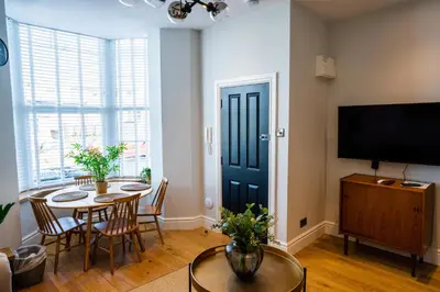 a living room with a table and chairs and a tv at Central, stylish 3 bed apartment with sea views in Newquay
