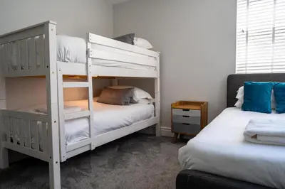 a bedroom with two bunk beds and a couch at Central, stylish 3 bed apartment with sea views in Newquay