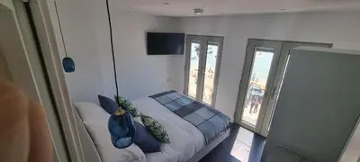 a bedroom with a bed with blue pillows and a window at Chy Mor Apartment 2 - Stunning sea views on the harbour in St Ives