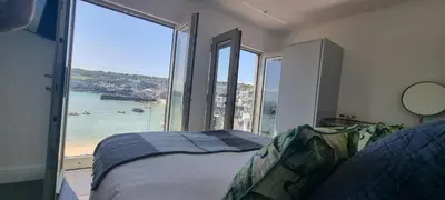 a bedroom with a bed and a view of the ocean at Chy Mor Apartment 2 - Stunning sea views on the harbour in St Ives