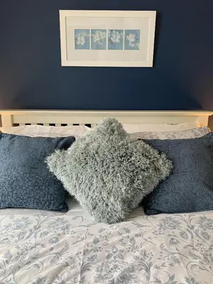 a bed with two pillows and a blue wall at Headland View. Luxury. Harbour-Front. With Parking in Falmouth