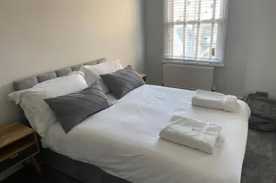 a large white bed with two towels on it at Beachside apartment in the centre of town in Newquay