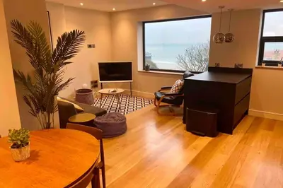 a living room with a table and a tv at Beachside apartment in the centre of town in Newquay