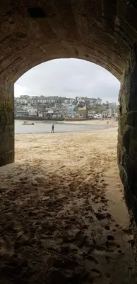 a person walking on the beach under a bridge at Stargazy Shepherds Hut in St Ives