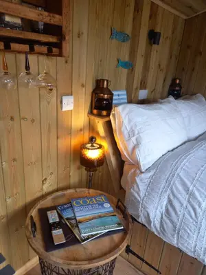 a bedroom with a bed and a table with a book at Stargazy Shepherds Hut in St Ives