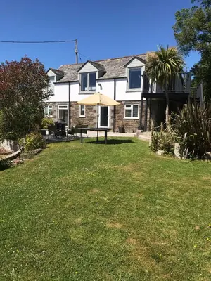a house with a lawn in front of it at The Barn at Well Cottage in Bude
