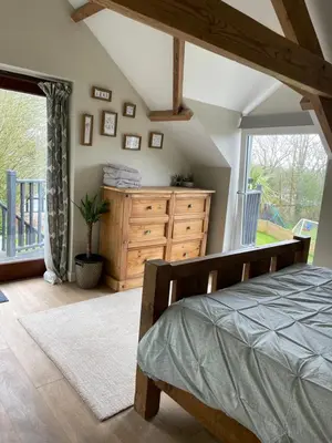 a bedroom with a bed and a dresser and a window at The Barn at Well Cottage in Bude