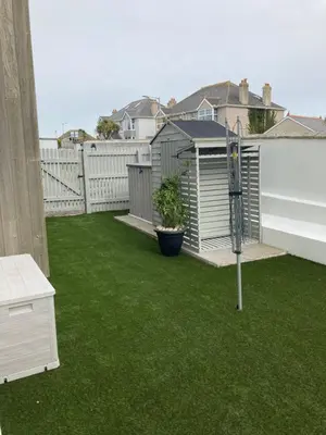 a small backyard with green grass and a basketball hoop at Beautiful 3 bedroom apartment by the Sea in Newquay
