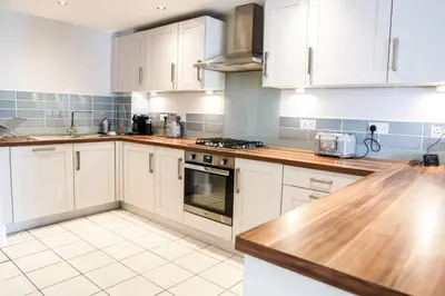 a kitchen with white cabinets and wooden counter tops at Beautiful 3 bedroom apartment by the Sea in Newquay