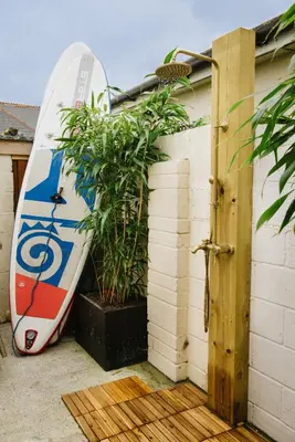 a surfboard leaned up against a wall next to a plant at Finest Retreats - Atlantic Hideaway in Newquay