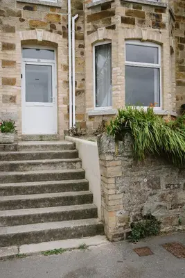 a brick building with a white door and stairs at Finest Retreats - Atlantic Hideaway in Newquay
