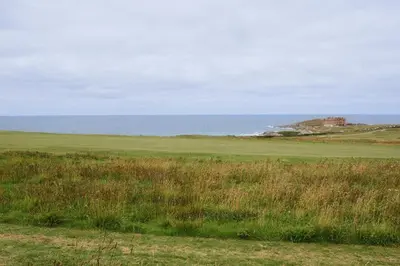 a field of grass with the ocean in the background at Finest Retreats - Atlantic Hideaway in Newquay