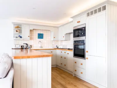 a white kitchen with white cabinets and a counter top at Slipway 21 in Padstow