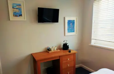 a room with a table with a tv on the wall at Seven Bays Stays in St Merryn