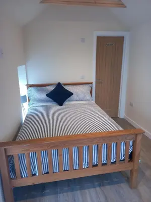 a bed with a wooden frame in a room at Seven Bays Stays in St Merryn