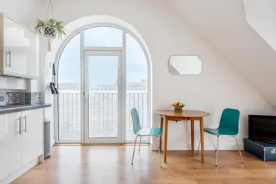 a kitchen with a table and chairs and a window at Bells Chapel - Bright Rooftop Apartment in the Centre of Town with Juliet Balconies in Falmouth