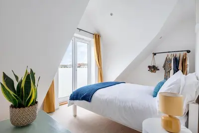 a white bedroom with a bed and a window at Bells Chapel - Bright Rooftop Apartment in the Centre of Town with Juliet Balconies in Falmouth