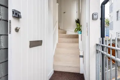 a hallway with a white door and stairs at Bells Chapel - Bright Rooftop Apartment in the Centre of Town with Juliet Balconies in Falmouth