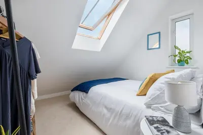 a white bedroom with a bed and a window at Bells Chapel - Bright Rooftop Apartment in the Centre of Town with Juliet Balconies in Falmouth