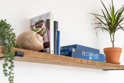 a wooden shelf with books and plants on it at Bells Chapel - Bright Rooftop Apartment in the Centre of Town with Juliet Balconies in Falmouth