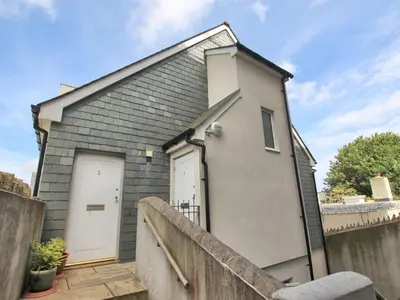 a small house with two doors and a fence at Bells Chapel - Bright Rooftop Apartment in the Centre of Town with Juliet Balconies in Falmouth