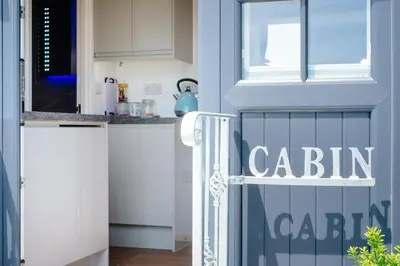 a kitchen with white cabinets and a door with the word cabin at Mount View Overnight Accommodation in Penzance
