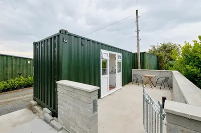 a green shipping container with a patio and a table at Mount View Overnight Accommodation in Penzance