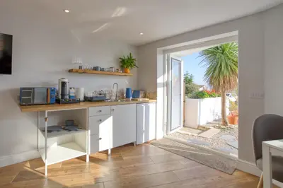 a kitchen with white cabinets and a door leading to a patio at Pebbles - A relaxing King Studio in St Ives