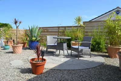 a patio with chairs and a table and plants at Pebbles - A relaxing King Studio in St Ives