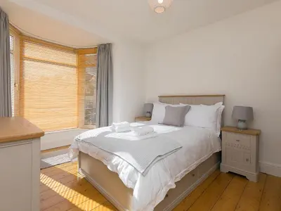 a white bedroom with a large bed and a window at Trengoff in St Ives