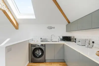a kitchen with a washing machine in the middle at Cedar House in St. Agnes