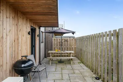 a patio with a table and an umbrella and a grill at Cedar House in St. Agnes