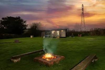 a fire pit in the middle of a field with a building at Nori's Nest, Croft Hooper - Hot Tub - Free WiFi & Parking - Fire Pit in Ludgvan