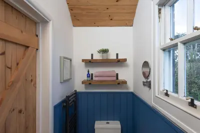a bathroom with a blue toilet and a wooden door at Nori's Nest, Croft Hooper - Hot Tub - Free WiFi & Parking - Fire Pit in Ludgvan