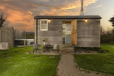 a tiny house with a table and chairs in a yard at Nori's Nest, Croft Hooper - Hot Tub - Free WiFi & Parking - Fire Pit in Ludgvan