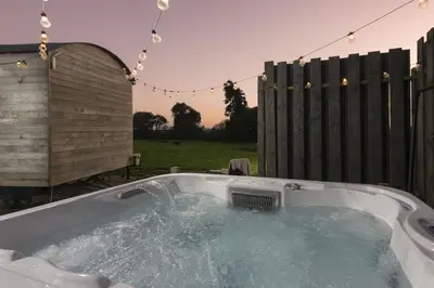 a jacuzzi tub in a backyard with a fence at Nori's Nest, Croft Hooper - Hot Tub - Free WiFi & Parking - Fire Pit in Ludgvan