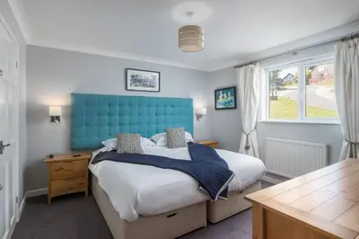 a bedroom with a bed and a blue headboard at Lodge 27 - Resort & Spa - Parking - Private Hot Tub in Saint Columb Major