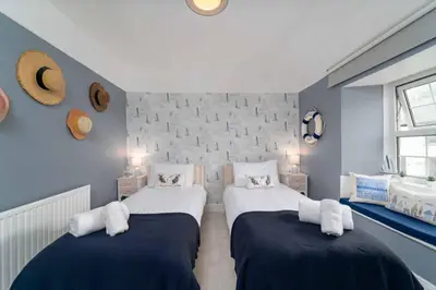 two beds in a room with blue walls at Curlew Cottage in Uny Lelant
