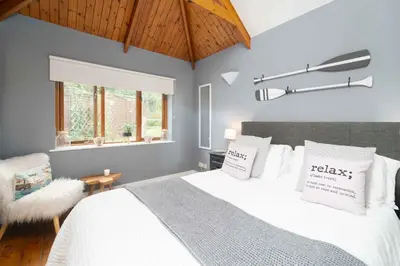 a bedroom with a bed with white sheets and a window at Curlew Cottage in Uny Lelant