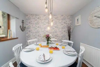 a white dining room with a white table with fruit on it at Curlew Cottage in Uny Lelant