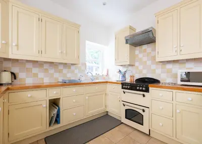 a kitchen with white cabinets and a stove top oven at The Terrace 2 in Padstow