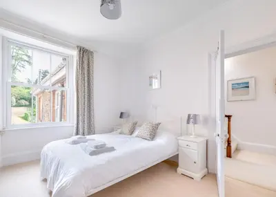 a white bedroom with a bed and a window at The Terrace 2 in Padstow