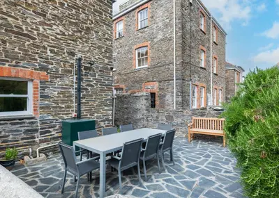 a patio with a table and chairs in front of a brick building at The Terrace 2 in Padstow