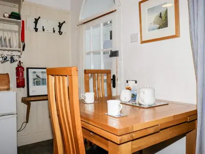 a kitchen with a wooden table with two chairs at Destiny Cottage in Boscastle