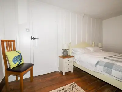 a bedroom with a bed and a chair and a door at Destiny Cottage in Boscastle