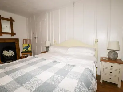a white bedroom with a bed and a fireplace at Destiny Cottage in Boscastle
