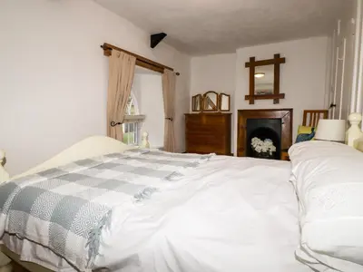 a bedroom with a white bed and a fireplace at Destiny Cottage in Boscastle