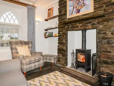 a living room with a fireplace and a couch and chair at Destiny Cottage in Boscastle