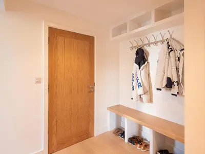 a hallway with a wooden door and clothes racks at Pentire in Saint Minver